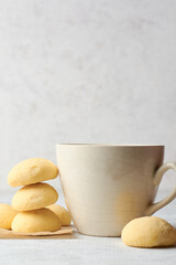 ghee biscuits or cookies on table with a tea cup, against blurry white textured background, homemade melt in mouth nei biscuits, eggless cookies are made whole wheat flour, selective focus, copy space