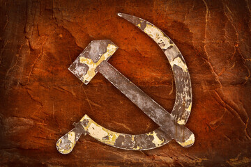 Weathered USSR hammer and sickle in front of an old brown background