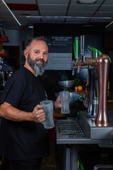 hombre barman con gorro de vaquero preparando un c&oacute;ctel azul en la barra del bar