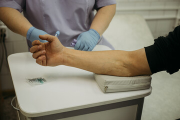 Fototapeta na wymiar arm to elbow, preparation for taking blood for laboratory testing. In the background, the silhouette of a nurse in medical gloves