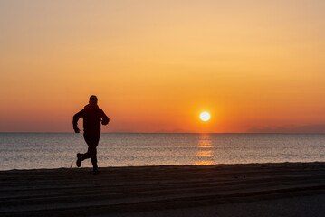Fototapeta na wymiar silhouette of a man running on the beach at sunset