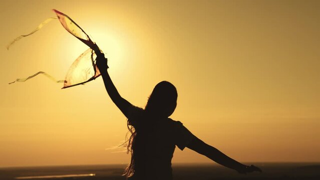 child launches kite sunset. silhouette teenage girl playing with wind sunset. happy family. childhood dream fly. flying a kite sky sunset. happy family concept. colored children toy with wind