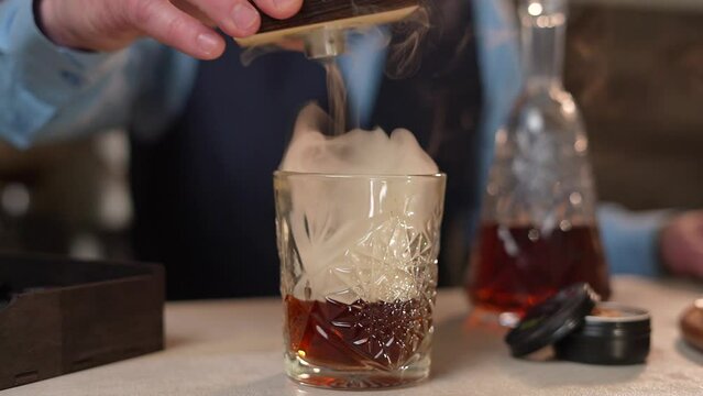 Bartender make whiskey for guests in the bar close-up. Smoky fire cocktail. Slow-mo