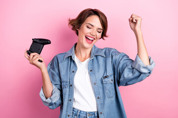 Photo of excited lucky woman wear jeans shirt winning playstation game isolated pink color background