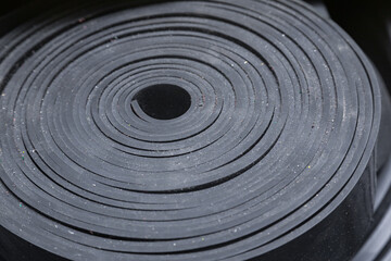 Industrial, new, black rubber twisted into a roll, close-up.
