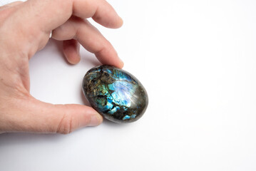 Hand holding a Labradorite polished mineral on white background