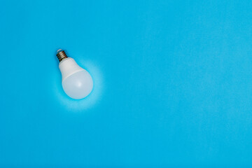 Energy-saving light bulb on a blue background with space for text.