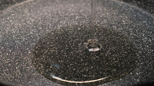 Sunflower oil is poured into the bottom of a frying pan close-up