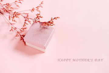 Festive pink background with a gift and a branch of flowers. Happy Mother's Day. copy space, banner, flyer