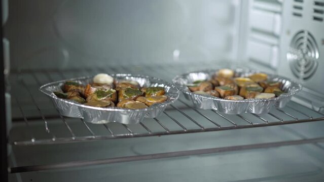 Plates with uncooked escargot on oven grid close-up. Tasty exotic food cooking indoors