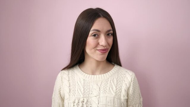 Young beautiful hispanic woman smiling confident doing yes gesture with head over isolated pink background