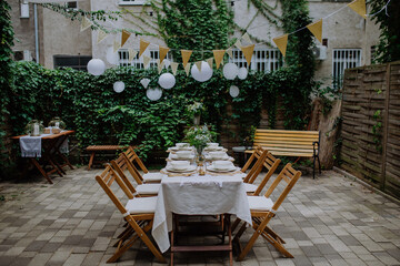 Fototapeta na wymiar Festive wedding table setting with flowers at small reception in backyard in summer.