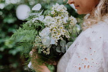Close-up of wedding bouquet in bride's hands at reception outside in backyard