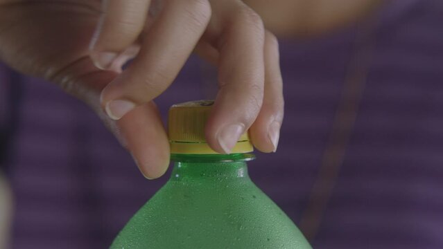 person opening a green soda bottle
