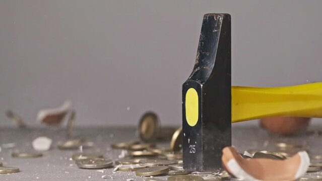 A hammer slowly break a ceramic piggy bank filled with coins in this impactful video on savings and financial security
