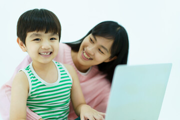 Happy Asian little young boy learning on laptop computer or notebook with his mother while stay at home in weekend.