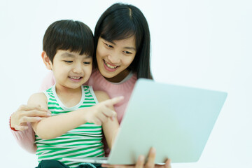 Happy Asian little young boy learning on laptop computer or notebook with his mother while stay at home in weekend.