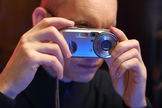 a person holds an old compact camera near the eyes