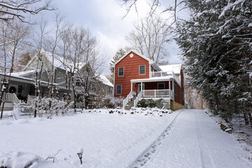 red suburban house with front yard and driveway covered with snow after snow storm