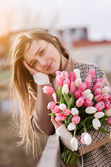Beautiful girl with tulip flowers in her hands walks in the park  