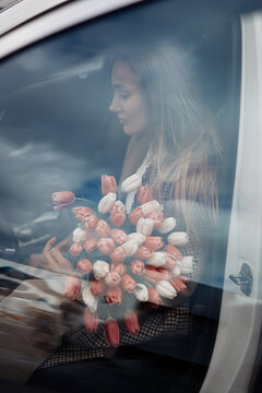 Beautiful girl with tulip flowers in her hands in the car 
