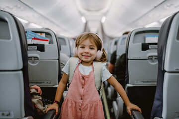Happy little girl standing in aisle in the plane.