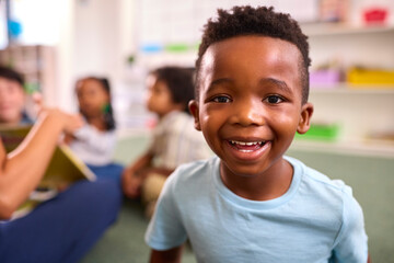 Portrait Of Smiling Male Elementary School Pupil Sitting In Classroom At  School