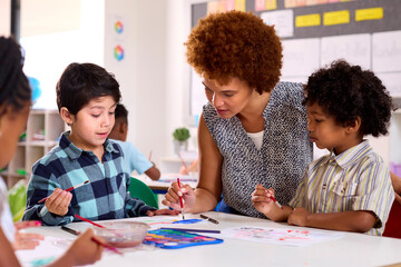 Female Teacher With Multi-Cultural Elementary School Pupils In Art Class At School