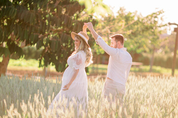 Casal mãe grávida e pai dançando ao ar livre no campo de flores na primavera 