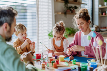 Happy family with little kids decorating easter eggs.