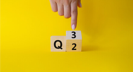From 2nd Quarter to 3rd symbol. Businessman hand points at turned wooden cube with words 2nd Quarter and 3rd Quarter. Beautiful yellow background. Business and Quarter concept. Copy space