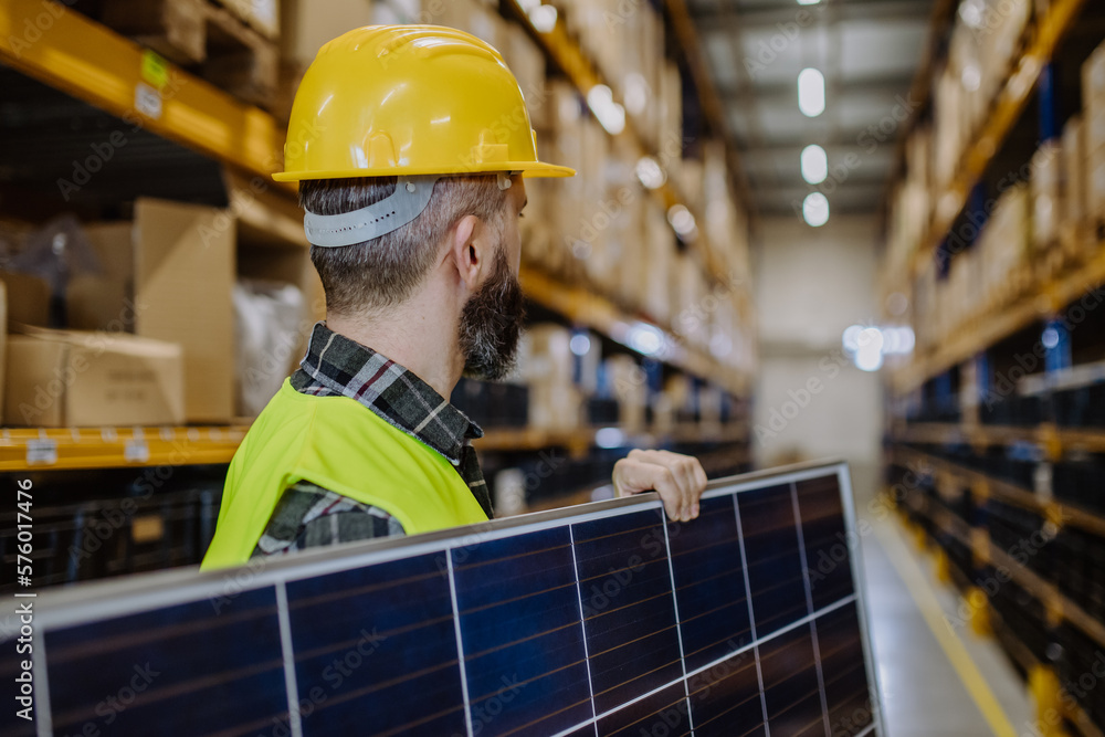 Poster Rear view of warehouse worker carring solar panel.