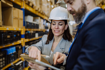 Managers in suit controlling goods in a waehouse.
