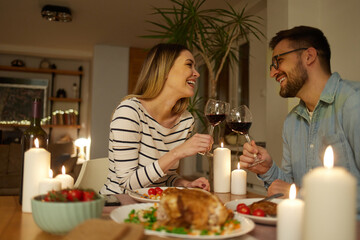 Beautiful couple having romantic dinner with candles and red wine at home