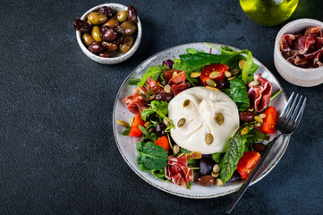 Burrata, Italian fresh cheese made from cream and milk of buffalo or cow. Burrata salad with tomatoes and salad mix. Healthy eating concept. Keto diet salad.