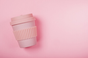 Reusable eco friendly bamboo cup for take away coffee on pink background. Flat lay, top view. Bring your own cup, sustainable lifestyle, zero waste and plastic free concept.
