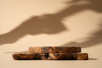 Wooden podium for cosmetic products, perfumes or food against beige background with leaves shadows....