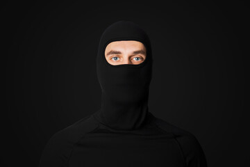 A man in a black mask. Thief, bandit. On a black background. Robbery.