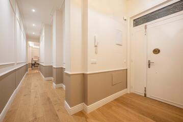 Long hall hallway of an empty house with white woodwork and laminated flooring