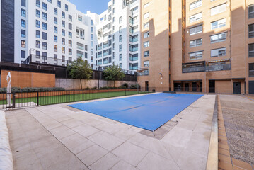 A summer pool covered with canvas to spend the winter in the common areas of an urbanization with...