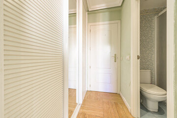 A bedroom walk-in wardrobe with sliding mirror doors and white Venetian wood next to an en-suite...