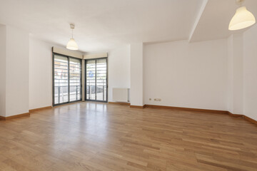 Empty room in a house with oak flooring, corner bay windows on two walls and wooden joinery