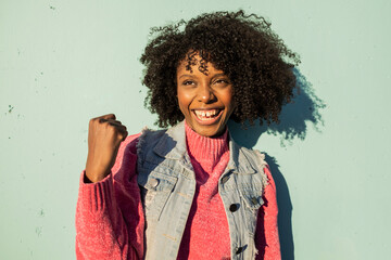 Happy young woman cheering in front of green wall