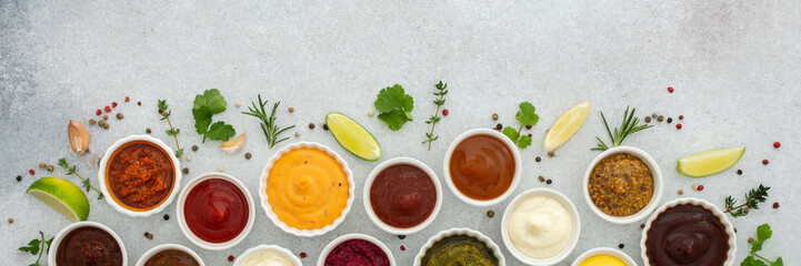 Different types of sauces in bowls with seasonings banner, rosemary and pepper, thyme and garlic, lime and lemon, cilantro, top view, copy space