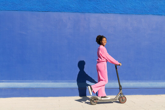 Happy woman riding electric push scooter on sunny day