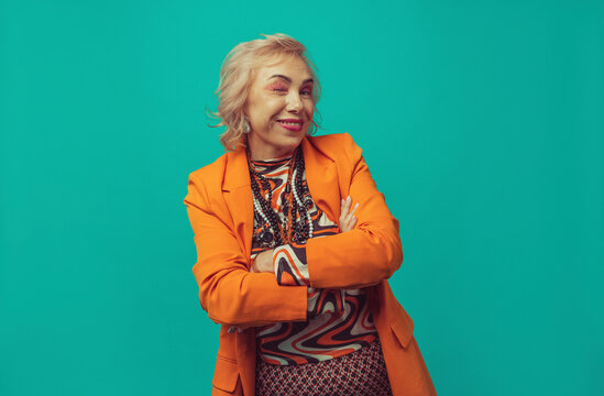 Woman with arms crossed winking against turquoise background