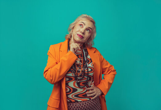 Thoughtful woman wearing blazer standing against colored background