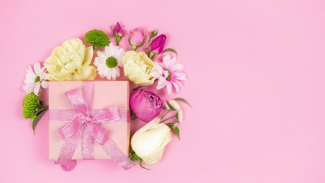 4k Happy mother's day, women's day, valentine's day or birthday holiday. Pastel pink background. Gift box beautifully decoreted natural flowers. Floral flat cards. Copy space. Stop motion animation.