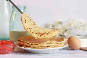 A stack of hot pancakes. Put a new crepes on a stack of ready-made pancakes. Large round thin...