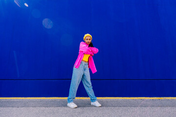 Dancer with arms crossed standing in front of blue wall
